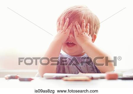Boy sitting at table resting on elbows, mouth open, covering eyes with hands View Large Photo Image Stock Image - Boy sitting at table resting on elbows, mouth open, covering eyes with hands. Fotosearch
