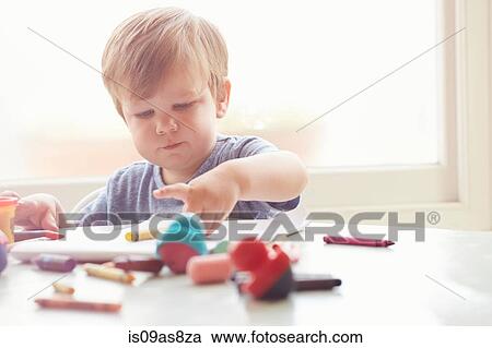 Boy sitting at table using art supplies View Large Photo Image Stock Image - Boy sitting at table using art supplies. Fotosearch
