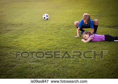 Boy tending injured younger sister on football practice pitch View Large Photo Image Stock Photo - Boy tending injured younger sister on football practice pitch. Fotosearch