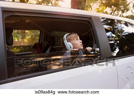 Boy wearing headphones gazing out of car window View Large Photo Image Stock Image - Boy wearing headphones gazing out of car window. Fotosearch
