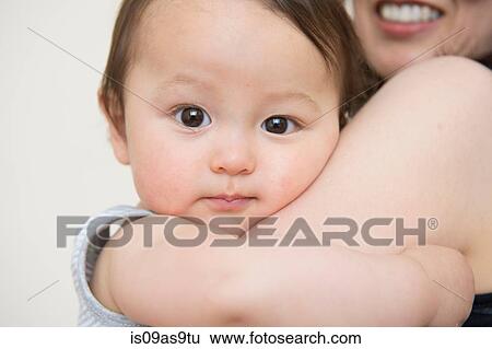 Stock Photograph - Close up portrait of cute baby boy in mature mothers arms. Fotosearch