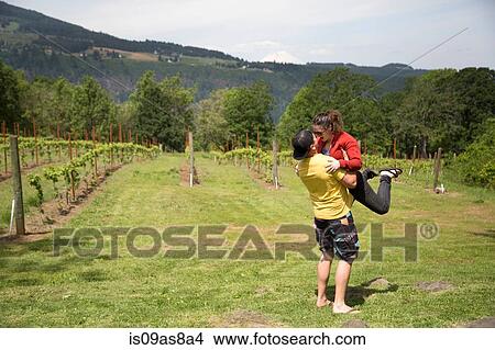 Couple embracing in field, man lifting woman in air View Large Photo Image Picture - Couple embracing in field, man lifting woman in air. Fotosearch