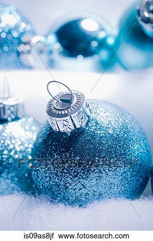 Stock Image - Cropped shot of blue sparkly Christmas baubles nested is fake snow. Fotosearch