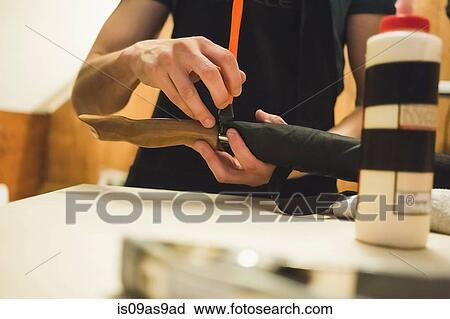 Stock Image - Cropped view of young man using tool to craft wood object. Fotosearch