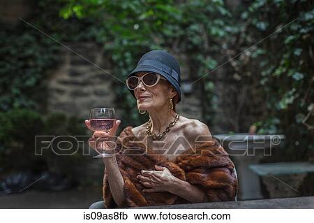 Stock Image - Fashionable senior woman in garden. Fotosearch