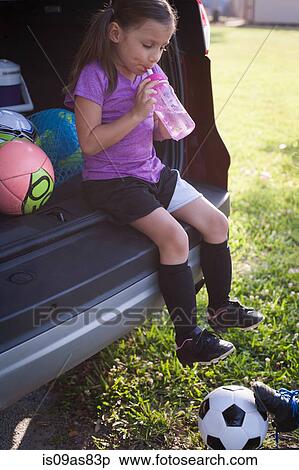 Girl football player sitting in car boot drinking water View Large Photo Image Stock Photography - Girl football player sitting in car boot drinking water. Fotosearch