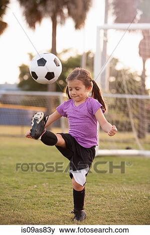 Girl kicking football on practice pitch View Large Photo Image Stock Photo - Girl kicking football on practice pitch. Fotosearch
