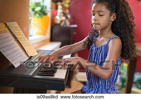 Stock Image - Girl sitting playing keyboard, looking down. Fotosearch