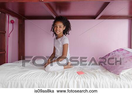 Girl wearing pyjamas kneeling on bed, looking at camera smiling View Large Photo Image Stock Image - Girl wearing pyjamas kneeling on bed, looking at camera smiling. Fotosearch