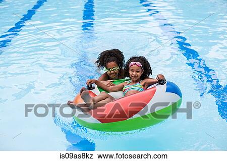 Girls in swimming pool playing with inflatable ring, looking at camera smiling View Large Photo Image Stock Photo - Girls in swimming pool playing with inflatable ring, looking at camera smiling. Fotosearch