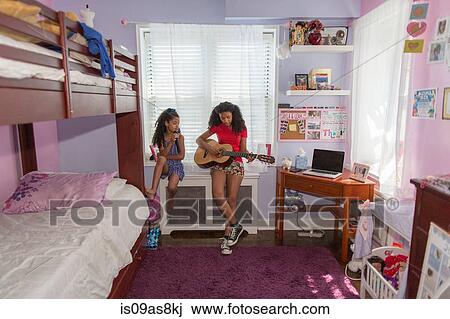Girls sitting on bedroom windowsill singing and playing guitar View Large Photo Image Stock Image - Girls sitting on bedroom windowsill singing and playing guitar. Fotosearch