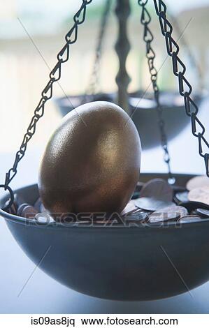 Golden egg on bed of coins in weighing scales View Large Photo Image Stock Photography - Golden egg on bed of coins in weighing scales. Fotosearch