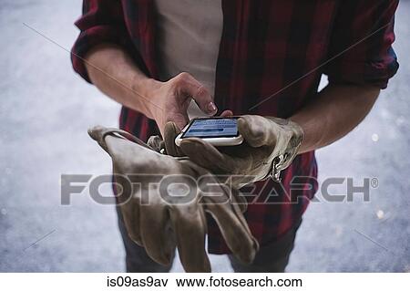 High angle cropped view of young mans hands wearing protective gloves using smartphone View Large Photo Image Stock Photo - High angle cropped view of young mans hands wearing protective gloves using smartphone. Fotosearch