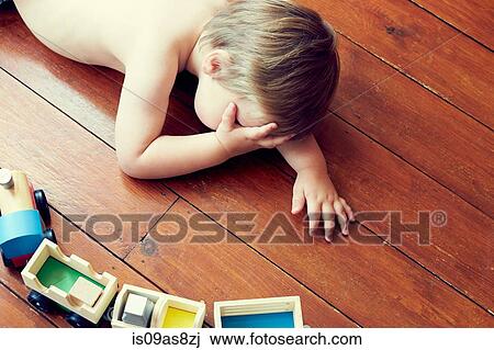 High angle view of boy lying on wooden floor by toy train, head in hand View Large Photo Image Stock Image - High angle view of boy lying on wooden floor by toy train, head in hand. Fotosearch