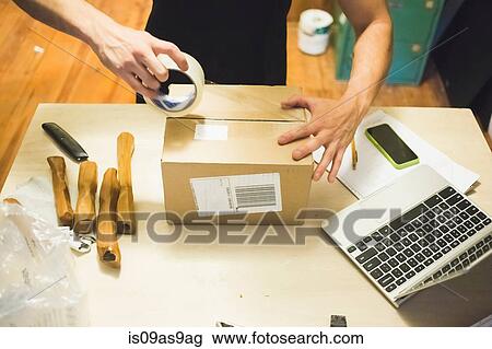 High angle view of young mans hands using sticking tape to prepare package for delivery View Large Photo Image Stock Image - High angle view of young mans hands using sticking tape to prepare package for delivery. Fotosearch