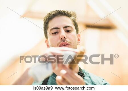 Stock Photo - Low angle view of young man crafting wood object, looking down. Fotosearch