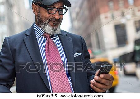 Stock Photography - Mature businessman using smartphone on street. Fotosearch