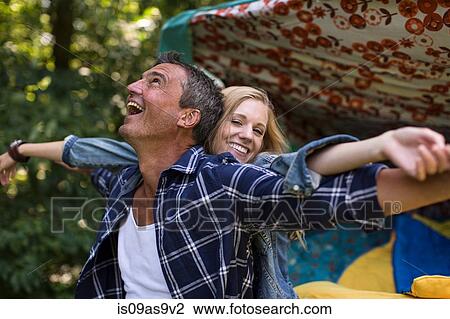 Stock Image - Mature man and girlfriend fooling around whilst camping. Fotosearch