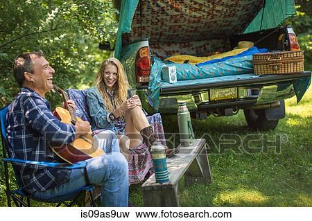 Mature man singing and playing acoustic guitar for girlfriend whilst camping View Large Photo Image Stock Photo - Mature man singing and playing acoustic guitar for girlfriend whilst camping. Fotosearch
