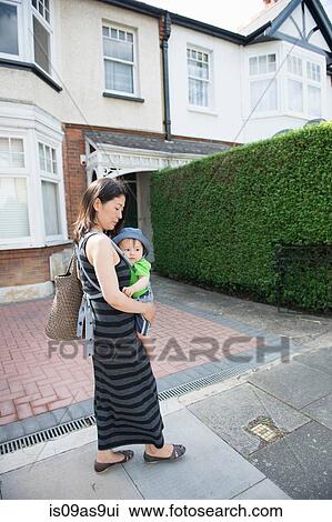Mature mother and son in baby sling strolling along street View Large Photo Image Stock Image - Mature mother and son in baby sling strolling along street. Fotosearch
