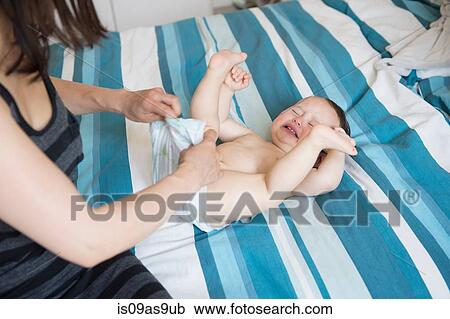Mature mother changing baby sons nappy on bed View Large Photo Image Stock Image - Mature mother changing baby sons nappy on bed. Fotosearch