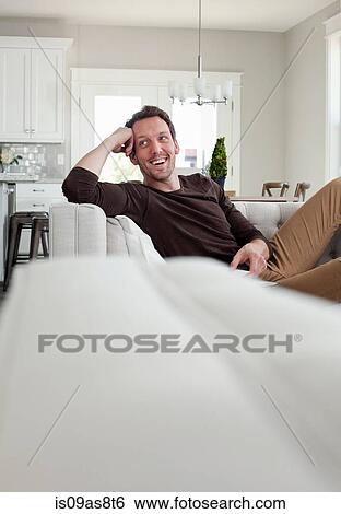 Stock Photograph - Mid adult man relaxing at home. Fotosearch