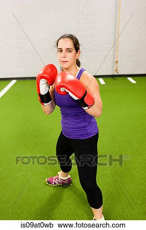 Mid adult woman wearing boxing gloves, working out in gym View Large Photo Image Stock Image - Mid adult woman wearing boxing gloves, working out in gym. Fotosearch