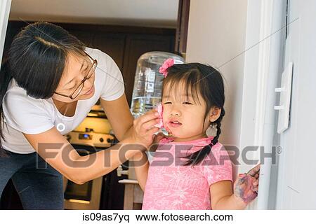 Stock Photography - Mother wiping daughter's face. Fotosearch