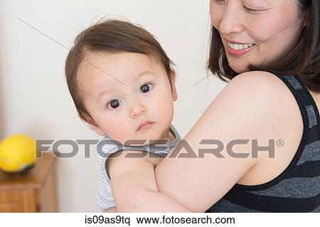 Stock Photography - Portrait of cute baby boy in mature mothers arms. Fotosearch