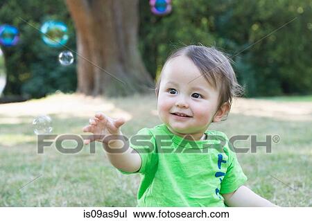 Portrait of cute baby boy reaching for bubbles in park View Large Photo Image Stock Image - Portrait of cute baby boy reaching for bubbles in park. Fotosearch