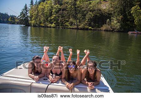 Stock Image - Portrait of four young women lying on motorboat at Lake Oswego, Oregon, USA. Fotosearch