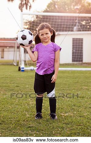 Portrait of girl football player holding up football on practice pitch View Large Photo Image Stock Photo - Portrait of girl football player holding up football on practice pitch. Fotosearch