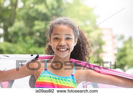 Stock Image - Portrait of girl holding towel arns open, looking at camera smiling. Fotosearch