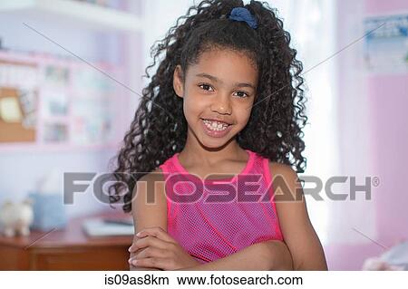 Picture - Portrait of girl with black curly hair, arms folded, looking at camera smiling. Fotosearch