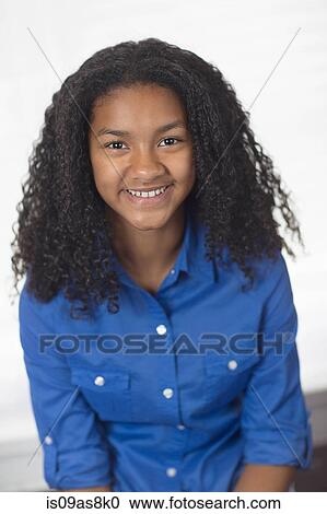Stock Image - Portrait of girl with curly black hair looking at camera smiling. Fotosearch
