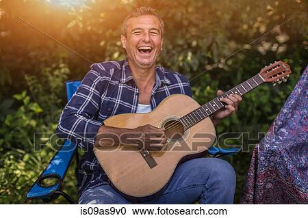 Portrait of mature man singing and playing acoustic guitar whilst camping View Large Photo Image Stock Image - Portrait of mature man singing and playing acoustic guitar whilst camping. Fotosearch