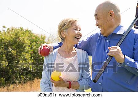 Stock Photography - Portrait of senior couple in park, holding croquet mallet and balls. Fotosearch
