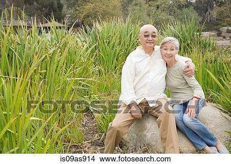 Picture - Portrait of senior couple sitting on rock. Fotosearch