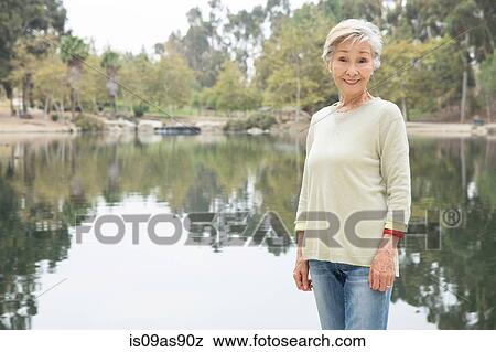 Portrait of senior woman standing beside lake View Large Photo Image Stock Photo - Portrait of senior woman standing beside lake. Fotosearch