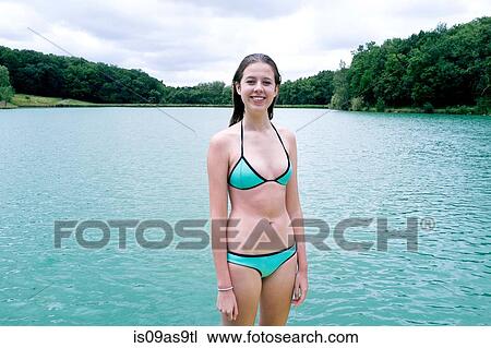 Stock Image - Portrait of teenage girl wearing bikini standing in front of lake, Tilac, South West France. Fotosearch