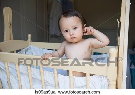 Portrait of tired baby boy standing in crib View Large Photo Image Stock Image - Portrait of tired baby boy standing in crib. Fotosearch