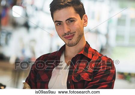 Stock Photograph - Portrait of young man wearing checked pattern shirt looking at camera smiling. Fotosearch