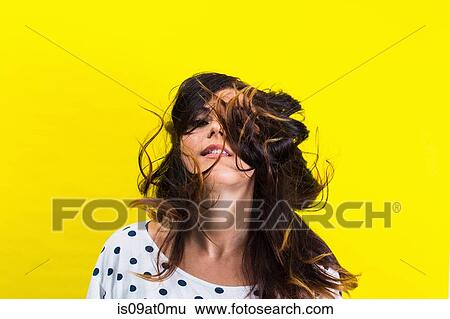 Stock Photograph - Portrait of young woman flicking hair. Fotosearch