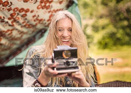 Portrait of young woman photographing with instant camera whilst camping View Large Photo Image Stock Photo - Portrait of young woman photographing with instant camera whilst camping. Fotosearch