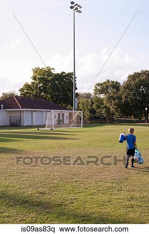 Rear view of boy football player carrying bag of footballs on practice pitch View Large Photo Image Stock Photography - Rear view of boy football player carrying bag of footballs on practice pitch. Fotosearch