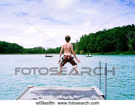Rear view of boy wearing swimming shorts jumping into lake, Tilac, South West France View Large Photo Image Picture - Rear view of boy wearing swimming shorts jumping into lake, Tilac, South West France. Fotosearch