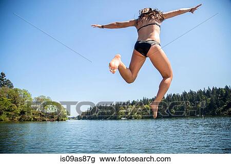 Rear view of young woman jumping into Lake Oswego, Oregon, USA View Large Photo Image Stock Image - Rear view of young woman jumping into Lake Oswego, Oregon, USA. Fotosearch