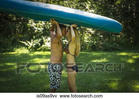 Romantic mature man kissing girlfriend whilst holding up kayak in garden View Large Photo Image Stock Photo - Romantic mature man kissing girlfriend whilst holding up kayak in garden. Fotosearch