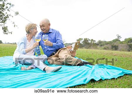 Senior couple having picnic in park, holding wine glasses View Large Photo Image Stock Image - Senior couple having picnic in park, holding wine glasses. Fotosearch