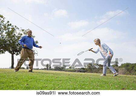 Stock Image - Senior couple playing badminton in park. Fotosearch